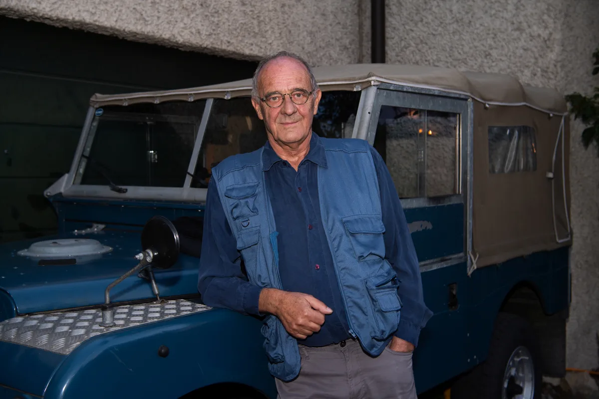 Jürg Peterhans mit Gilet vor einem älteren Auto.